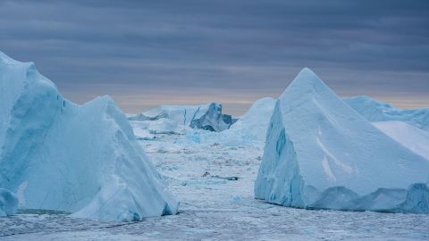 Warmer coastal water melts the Greenland ice sheet around the edges, breaking off massive icebergs that contribute to sea level rise.