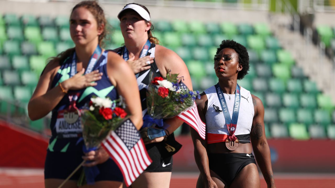 Gwen Berry, right, third place, looks on during the playing of the National Anthem with DeAnna Price, center, first place, and Brooke Andersen, second place, on the podium after the women's Hammer Throw final on day nine of the 2020 US Olympic Track & Field Team Trials at Hayward Field on June 26, 2021, in Eugene, Oregon.