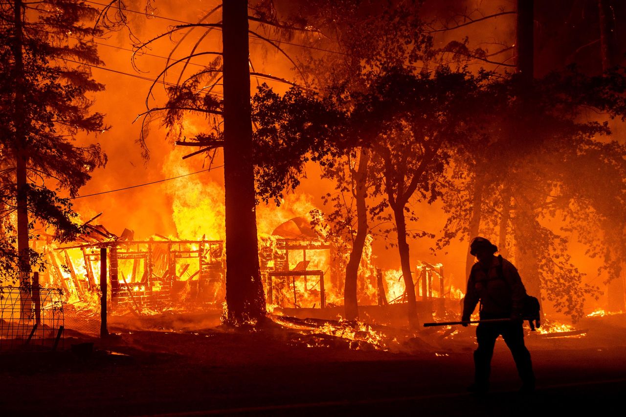 A firefighter passes a burning home as the Dixie Fire flares in Plumas County, California, on Saturday, July 24. The fire destroyed multiple residences as it tore through the Indian Falls community. <a href="http://www.cnn.com/2021/07/19/us/gallery/western-wildfires-2021/index.html" target="_blank">In pictures: Wildfires raging in the West</a>