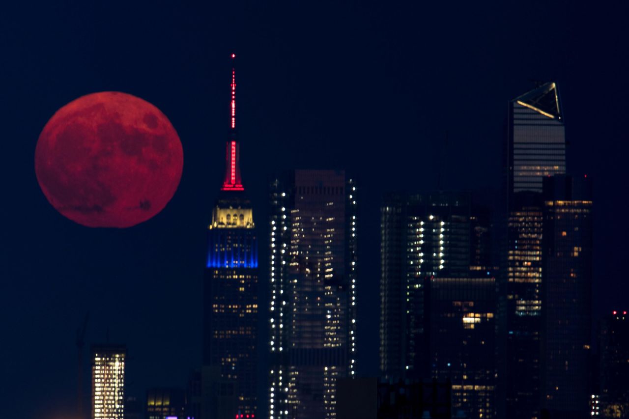 The full moon rises behind the Empire State Building in New York City on Friday, July 23.