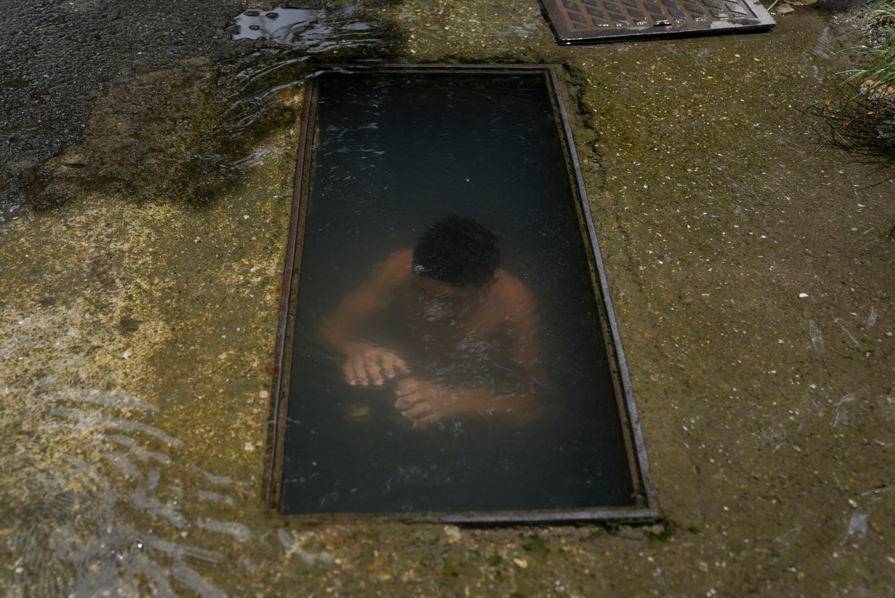 A boy cools off at the site of a broken water main in Caracas, Venezuela, on Tuesday, July 27.