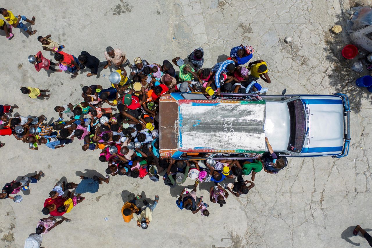 People gather around a car in Port-au-Prince, Haiti, on Monday, July 26, as volunteers distribute food at a shelter for <a href="https://www.cnn.com/2021/07/23/americas/haiti-moise-kidnappings-refugees-insecurity-intl-cmd/index.html" target="_blank">families displaced by gang violence.</a> Since June, more than 15,500 people in the city have had to flee their homes due to gang violence and rampant arson.
