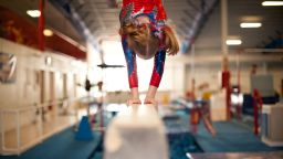 Young Gymnast Doing Handstand on Balance Beam - stock photo