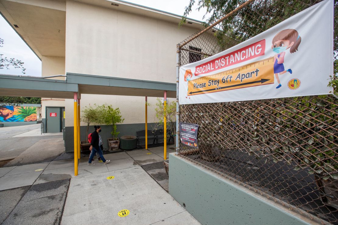 First grade student Daniel Cano, 5, and his mom, Sonia Cano, walk past Covid-19 safety precaution, social distancing and hand washing signs at a L.A. Unified "meet and greet" with its medical advisers.