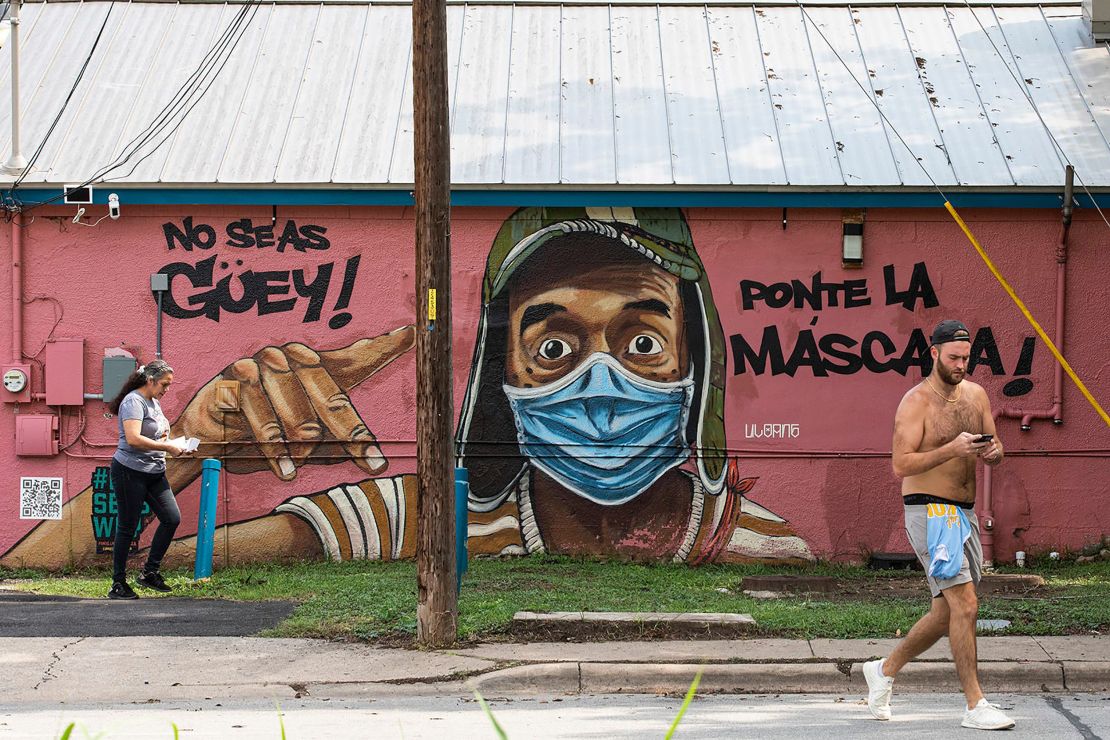 People pass a mural urging everyone to wear masks. The mural, seen on Tuesday, July 20, on Marcelino's restaurant in East Austin, translates to, "Don't be stupid. Put the mask on."