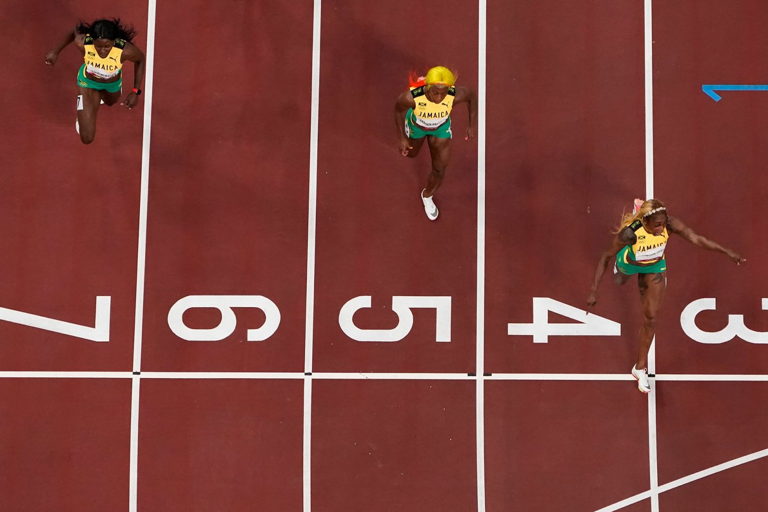 Thompson-Herah crosses the finish line first in the 100 meters. Fraser-Pryce, center, won this event in 2008 and 2012.