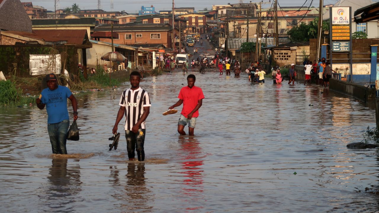 Residents wade through flooded Ige Road, in Aboru, Lagos, after a heavy downpour on July 6, 2020