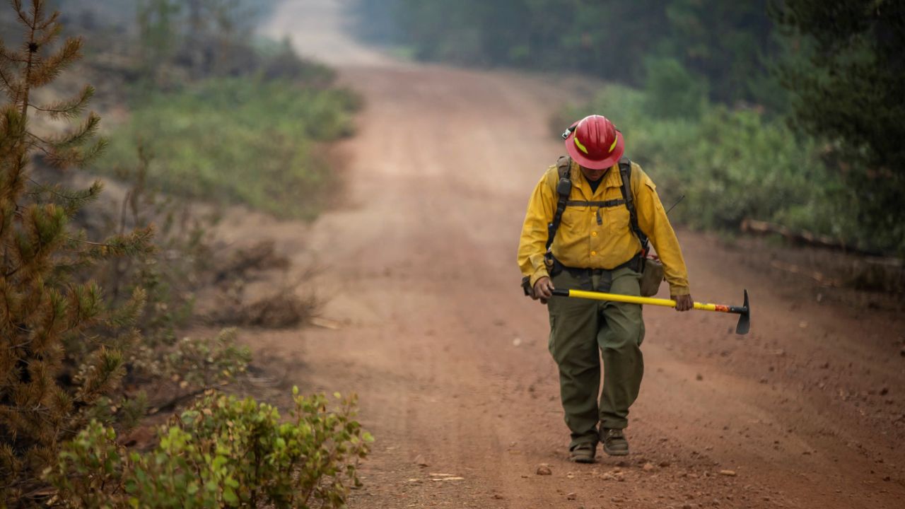 A firefighter from New Mexico walks up a dirt road after working to help contain the Bootleg Fire near Silver Lake, Oregon, on July 29, 2021.