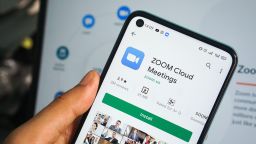 Zoom app display on smartphone, man's hand holding mobile phone