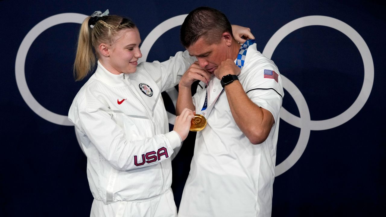Carey places her gold medal for the floor exercise over the neck of her dad and coach, Brian Carey.