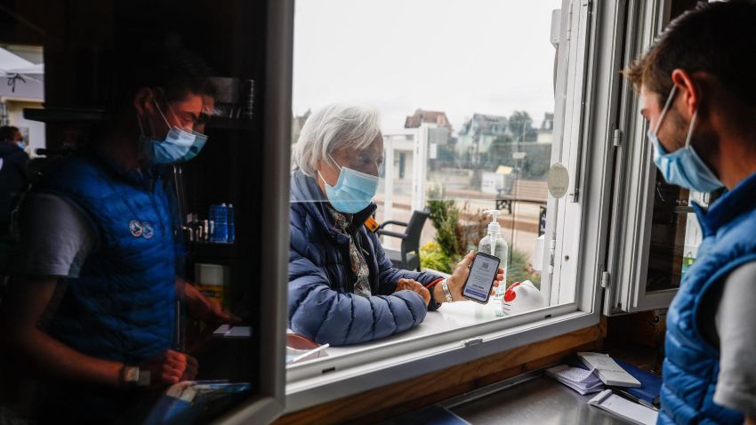 A man shows his health pass to a vendor before sitting at a coffee shop in Benerville-sur-Mer on July 27, 2021. - France's highest constitutional authority said on July 26, 2021 it would rule next week on new legislation passed by parliament that would make vaccine passes a key part of daily life. (Photo by Sameer Al-DOUMY / AFP) (Photo by SAMEER AL-DOUMY/AFP via Getty Images)