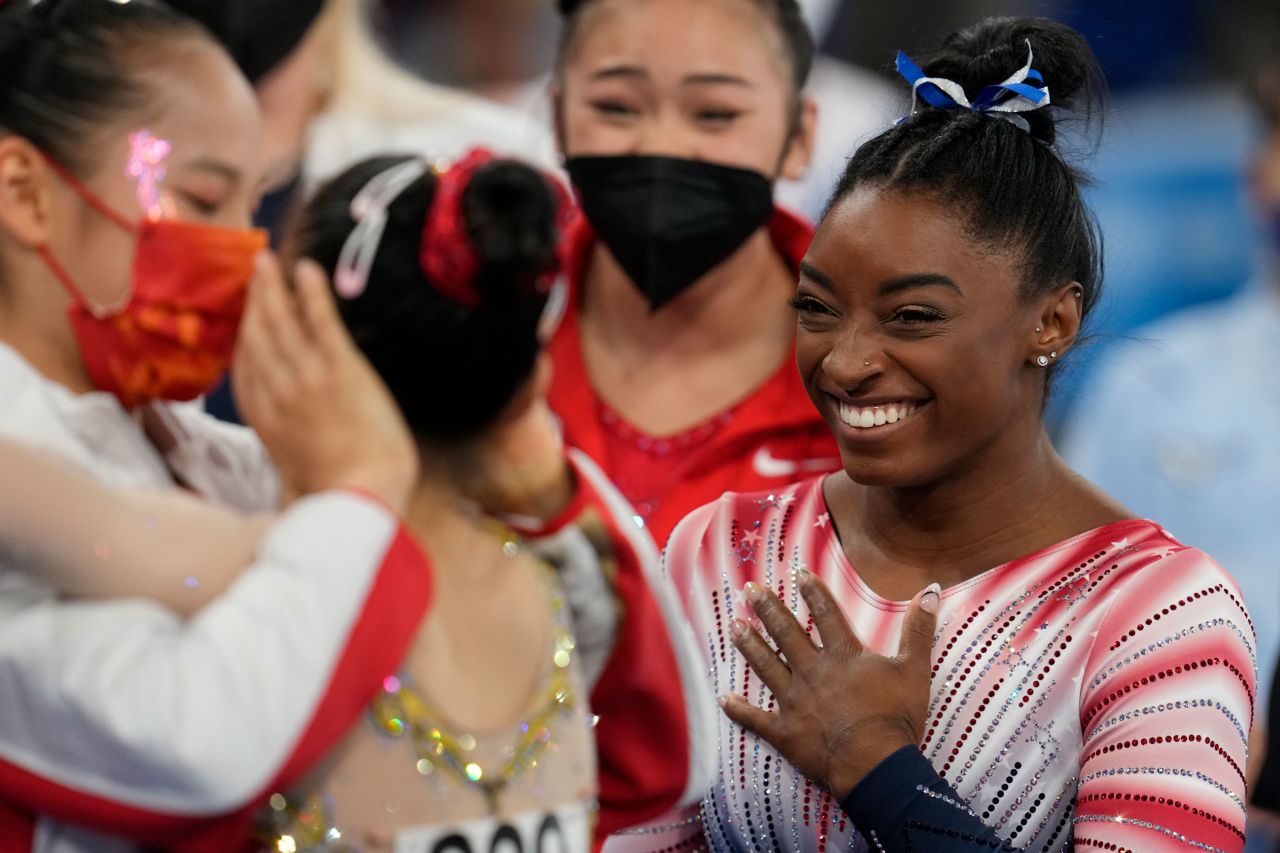 Biles watches Tang and Guan embrace after the event.