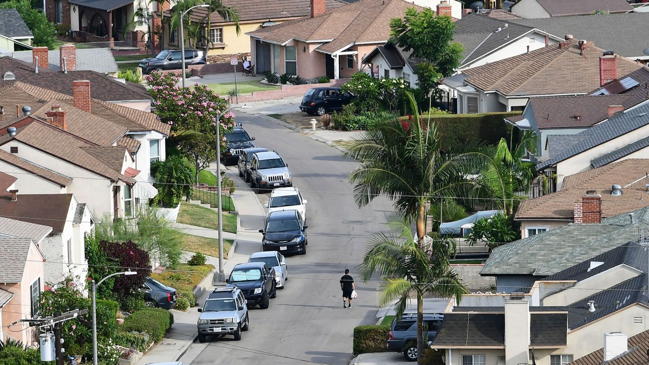 A man walks along a street in a neighborhood of single family homes in Los Angeles, California on July 30, 2021.