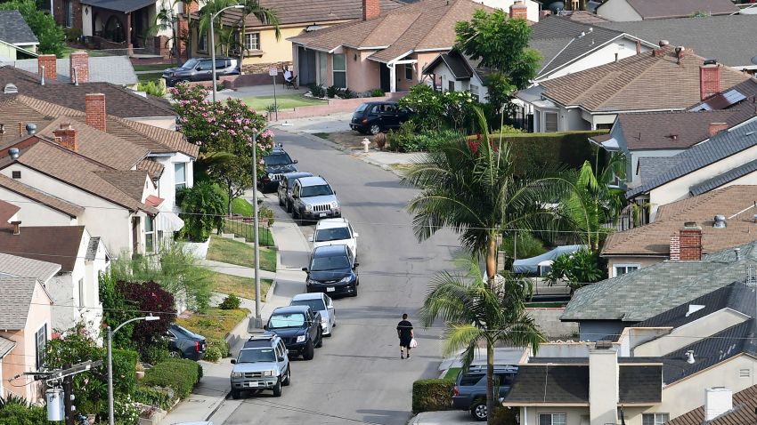 A man walks along a street in a neighborhood of single family homes in Los Angeles, California on July 30, 2021.