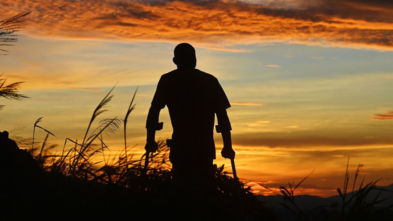 Alisandro Ramos, 41, who is on crutches after having had polio at the age of five, is seen during sunrise at the top of the Cerro Quezalapa in Canton Barahona, San Pedro Masahuat, 50 km from San Salvador, on September 5, 2020 amid the COVID-19 novel coronavirus pandemic. - Alisandro, who describes himself as an environmental guardian, lost his job to the pandemic and is now working as a tourist guide in his community. (Photo by Marvin RECINOS / AFP) (Photo by MARVIN RECINOS/AFP via Getty Images)