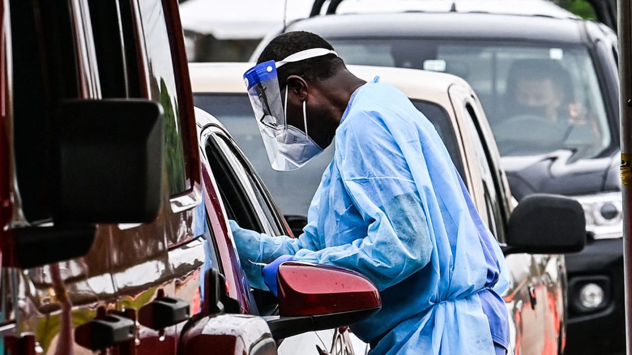 Medical personnel conduct Covid-19 testing at a "drive-through" site in Miami, on August 3, 2021. - In Florida cars are lining up for Covid-19 testings once again, amid record hospitalizations, as Florida Governor Ron DeSantis downplays the outbreaks severity, blaming media hysteria. (Photo by CHANDAN KHANNA / AFP) (Photo by CHANDAN KHANNA/AFP via Getty Images)