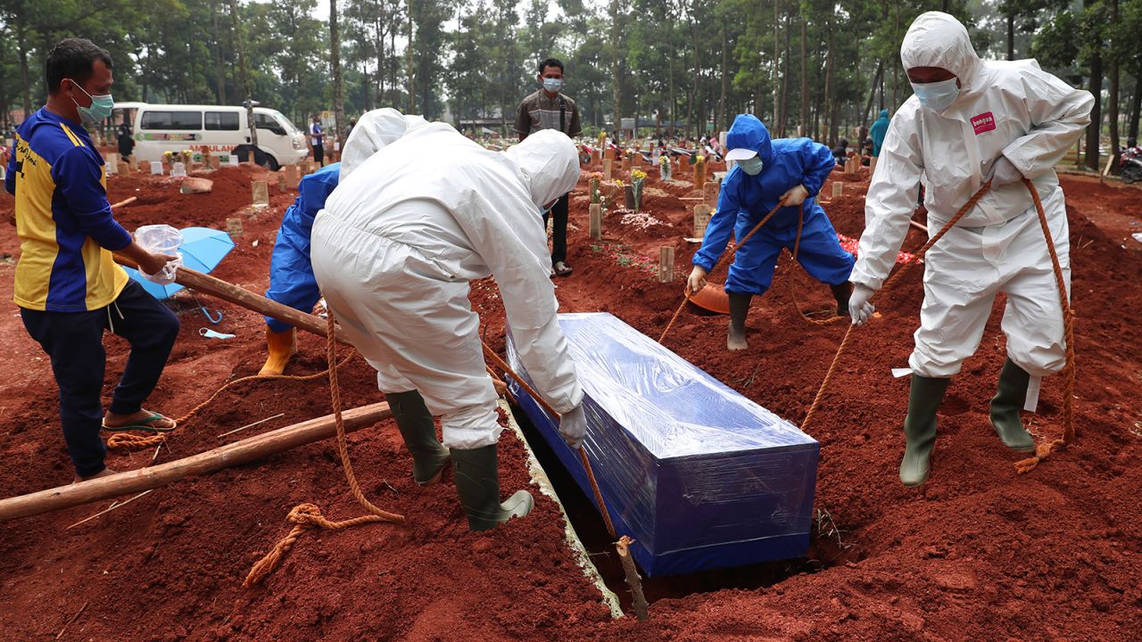 Workers in protective gear lower a coffin of a Covid-19 victim to a grave for burial at the Cipenjo Cemetery in Bogor, West Java, Indonesia, on July 14, 2021.