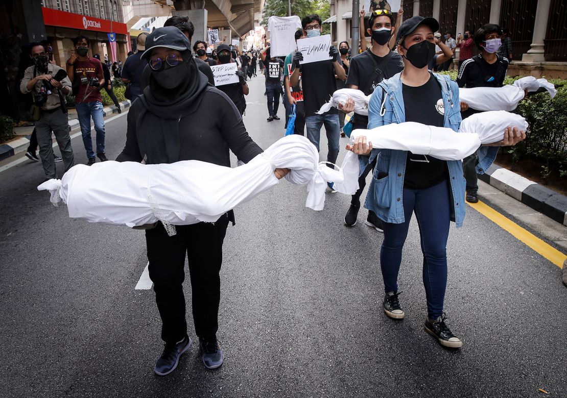 Protesters hold fake corpses during a demonstration near Independence Square in Kuala Lumpur, demanding the resignation of the prime minister over his handling of the coronavirus pandemic.