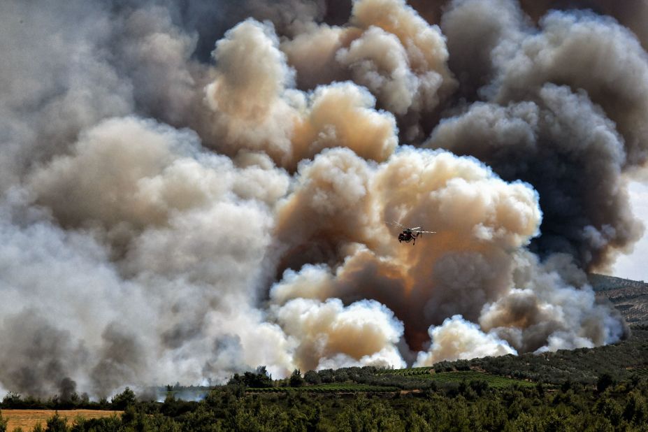 A firefighting helicopter passes in front of a cloud of smoke from a forest fire near Spathovouni village, southwest of Athens, Greece, on July 23.