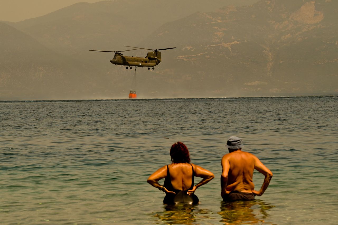 Local residents watch as a Greek army helicopter collects water to tackle a wildfire near the village of Lambiri, Greece, on August 1.