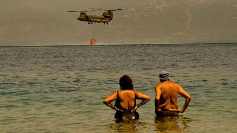 Local residents watch as a Greek army Chinook helicopter collects water to tackle a wildfire near the village of Lambiri, Greece, on Sunday, August 1.