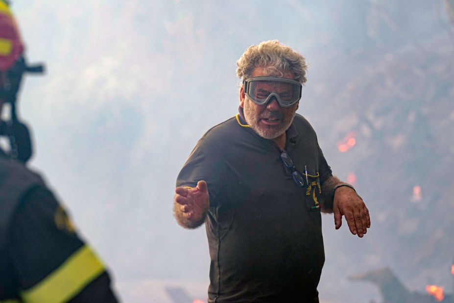 A firefighter talks to his colleague as they work to put out fires in Cuglieri, on the Italian island of Sardinia, on July 26.