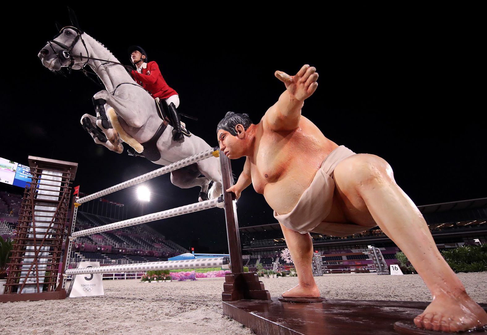 A statue of a sumo wrestler is seen near an obstacle as Japan's Koki Saito, aboard Chilensky, competes in jumping qualifiers on August 4. Riders said the lifelike statue <a href="index.php?page=&url=https%3A%2F%2Fapnews.com%2Farticle%2F2020-tokyo-olympics-equestrian-sumo-sculpture-8c9a3588952acf9502221636a5bf29d5" target="_blank" target="_blank">might have distracted some horses</a> during the competition.