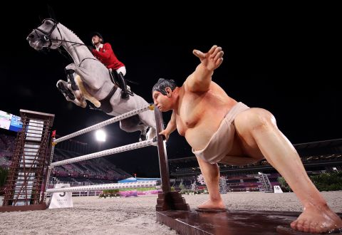 A statue of a sumo wrestler is seen near an obstacle as Japan's Koki Saito, aboard Chilensky, competes in jumping qualifiers on August 4. Riders said the lifelike statue <a href="https://apnews.com/article/2020-tokyo-olympics-equestrian-sumo-sculpture-8c9a3588952acf9502221636a5bf29d5" target="_blank" target="_blank">might have distracted some horses</a> during the competition.