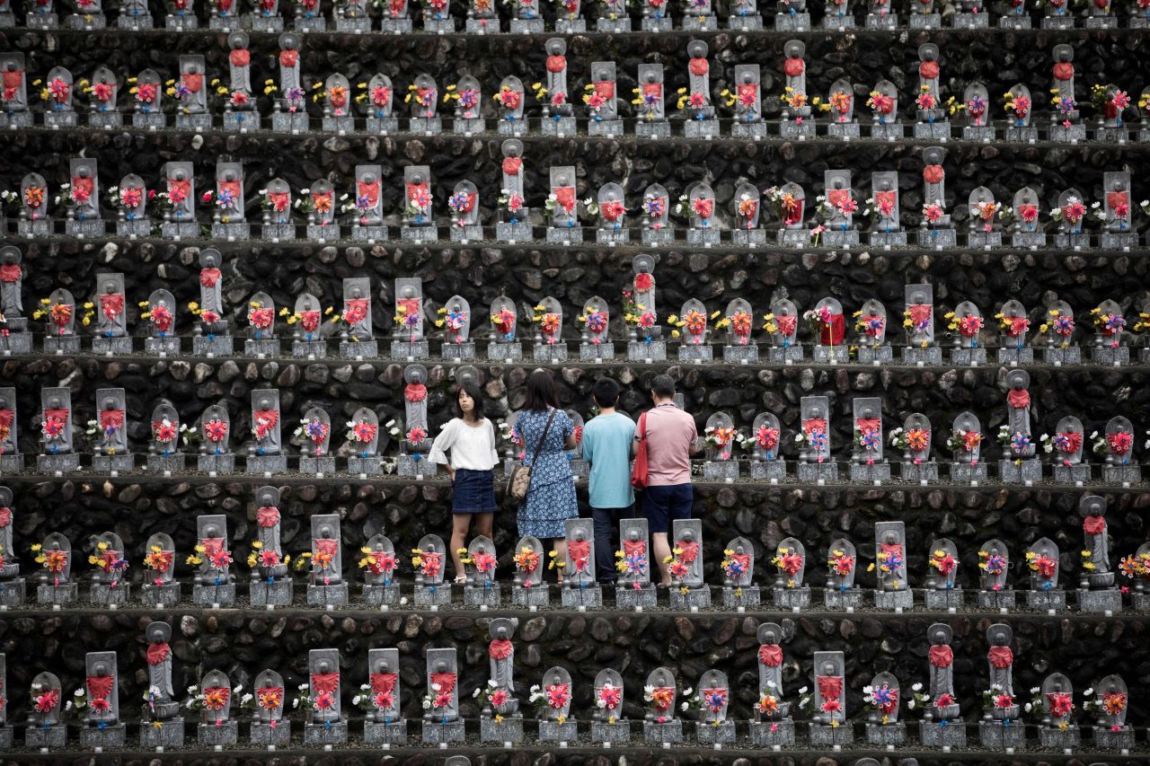 A family pays respects in front of jizo statues at a Buddhist temple in Japan's Saitama prefecture during the O-bon festival. 