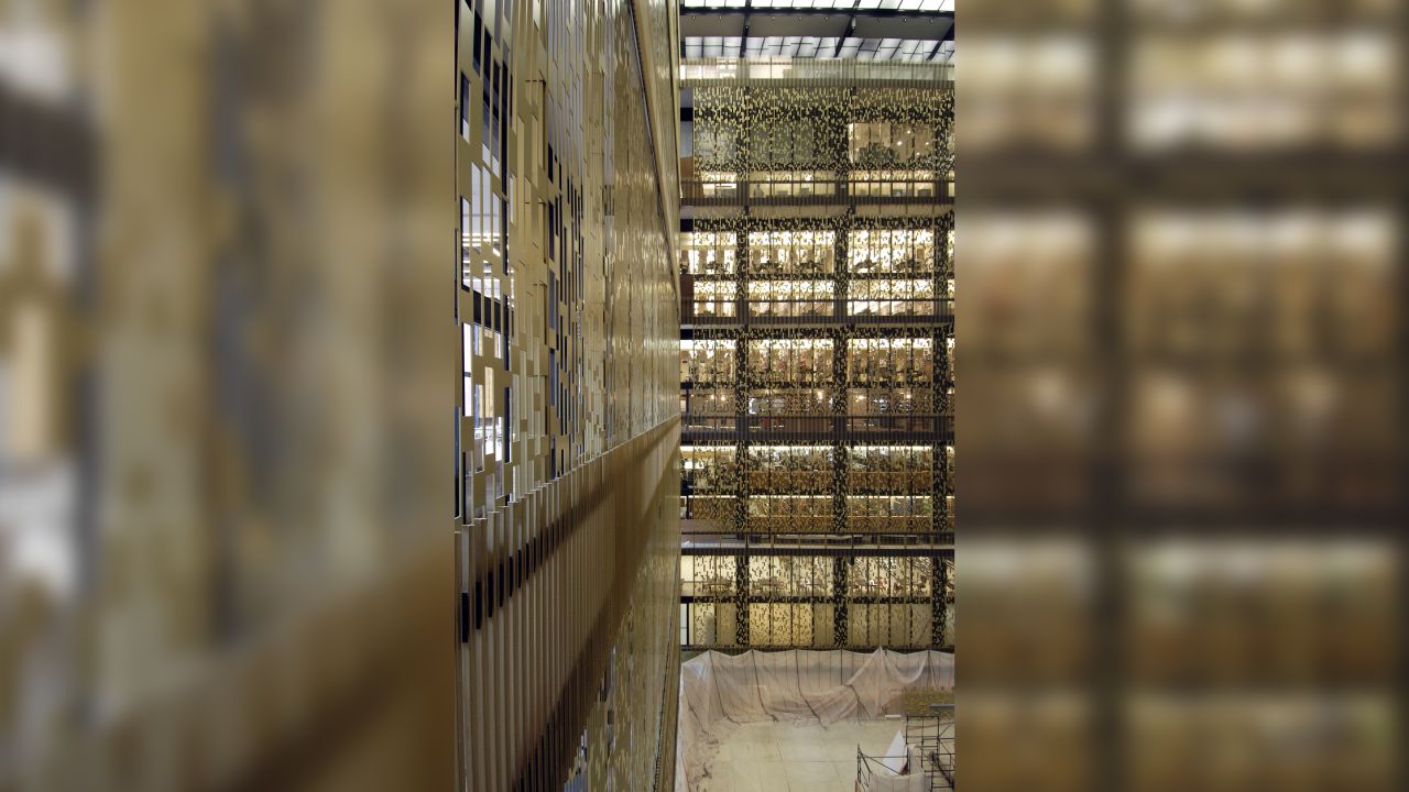 Perforated aluminum screens rise in the atrium of New York University's Elmer Holmes Bobst Library.