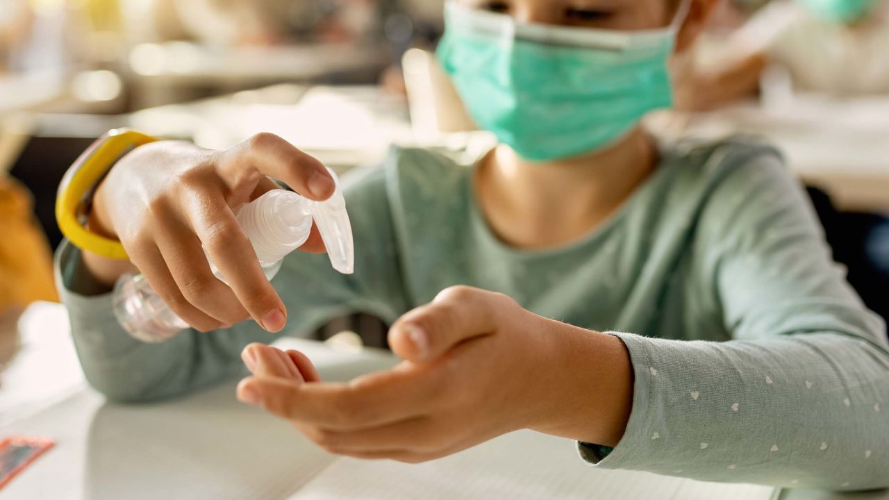 Close-up of elementary student disinfecting hands in the classroom due to COVID-19 pandemic.