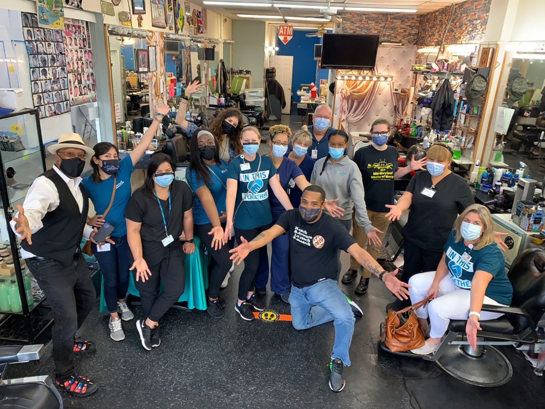 Mike Brown, kneeling in front, owner of The Shop Spa in Hyattsville, Maryland, hosted a vaccine clinic with local health professionals at his barbershop on May 17. More than 30 people were vaccinated that day.