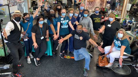 Mike Brown, kneeling in front, owner of The Shop Spa in Hyattsville, Maryland, hosted a vaccine clinic with local health professionals at his barbershop on May 17. More than 30 people were vaccinated that day.