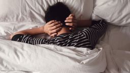 Preteen tween boy covering ears with his hands in bed