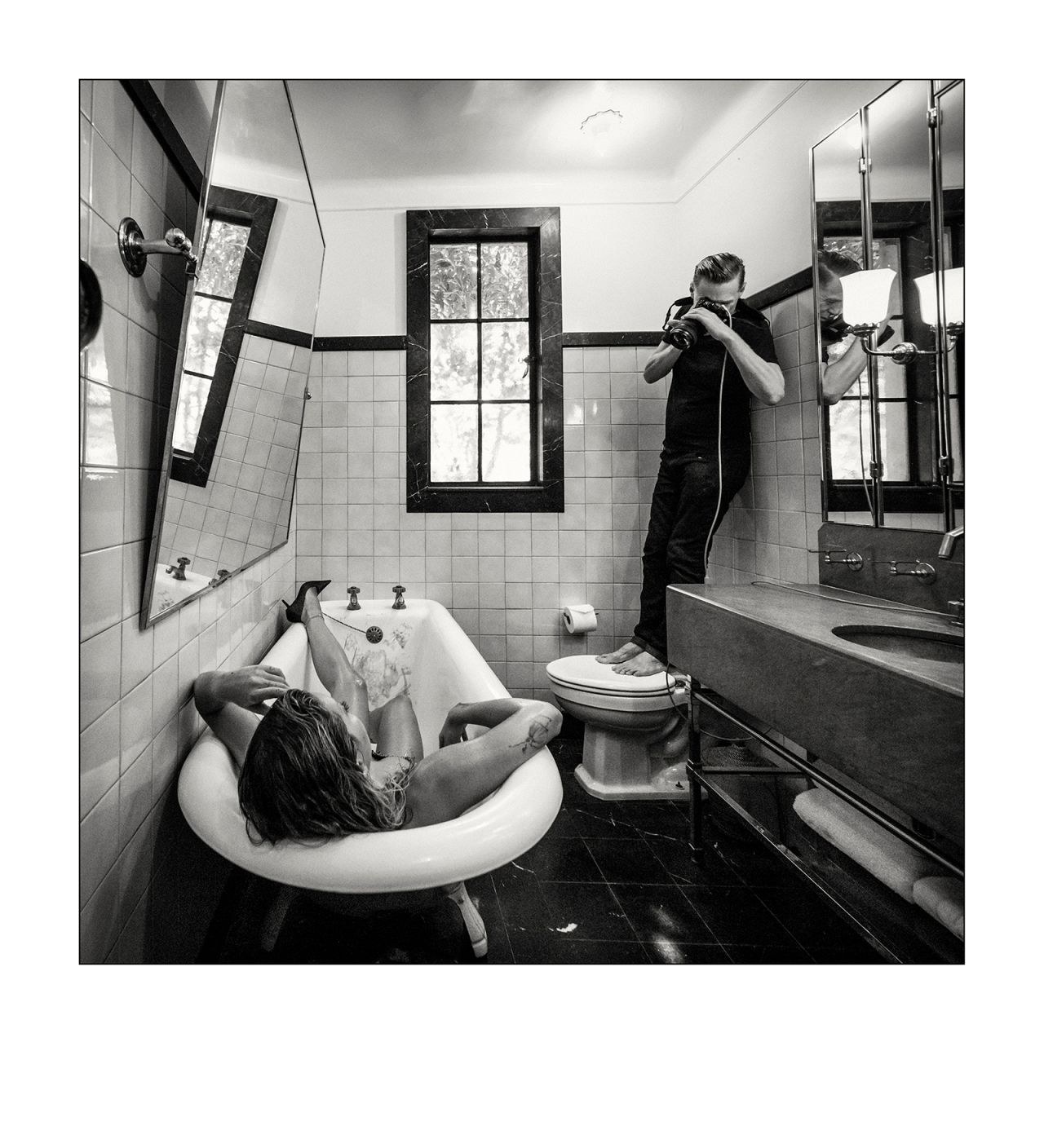 Rita Ora lies in a bathtub as photographer Bryan Adams shoots her from afar.