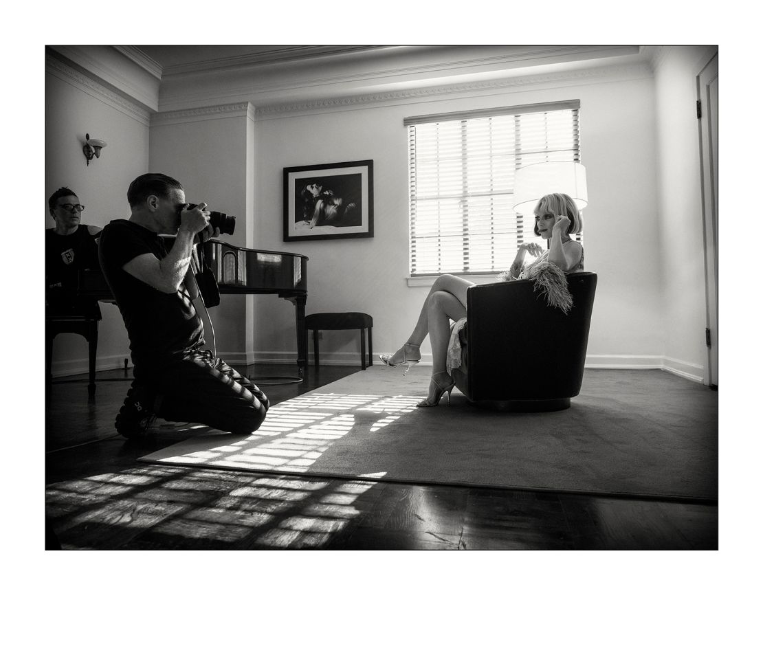 St Vincent sits in a chair as photographer Bryan Adams captures her portrait.