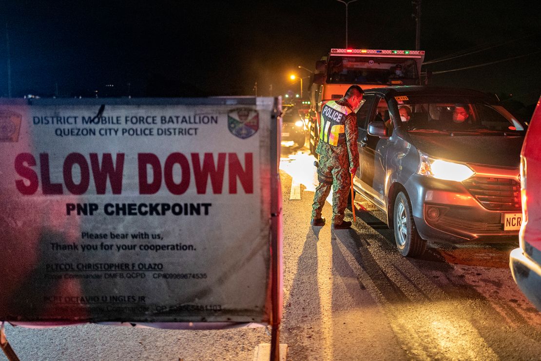 A police officer inspects motorists at a quarantine checkpoint on August 6 in Quezon city, Metro Manila, Philippines.