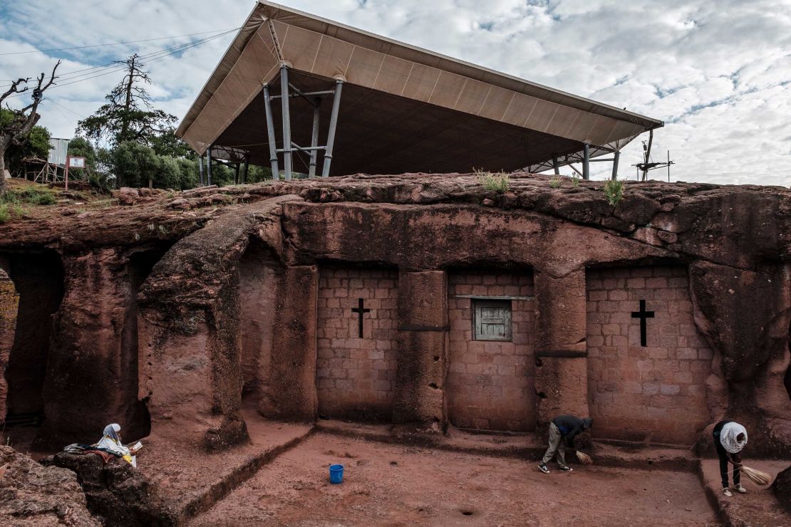 People stand next to the church of Saint Mercurius in Lalibela in 2019, which is covered by a shelter protecting its rock-hewn structure from erosion.