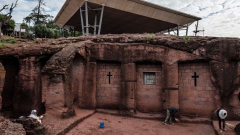 People stand next to the church of Saint Mercurius in Lalibela in 2019, which is covered by a shelter protecting its rock-hewn structure from erosion.