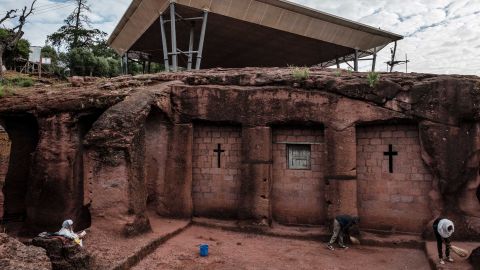 People stand next to the church of Saint Mercurius in Lalibela in 2019, which is covered by a shelter protecting its rock-hewn structure from erosion.