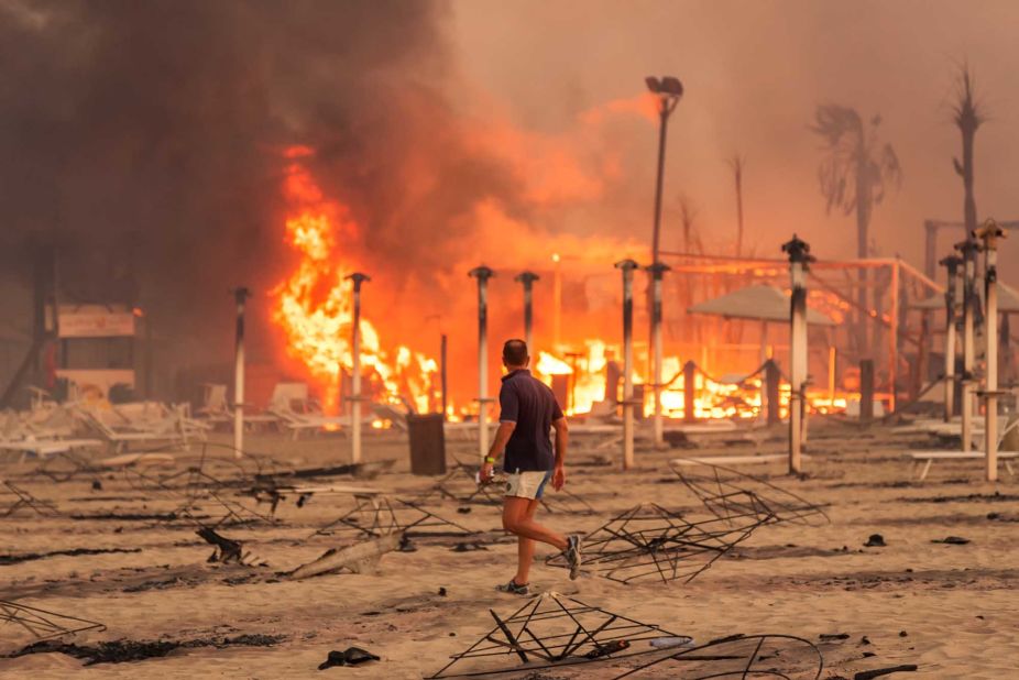 A man surveys a fire at Le Capannine beach in the Sicilian town of Catania, Italy, on July 30.