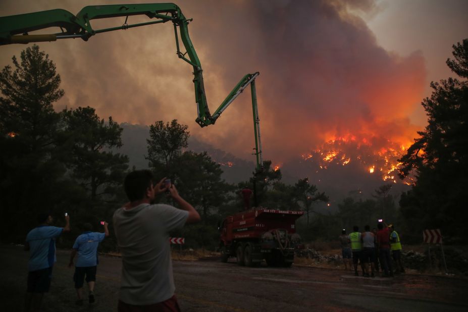 People watch an advancing fire that rages around the Cokertme village near Bodrum, Turkey, on August 2.