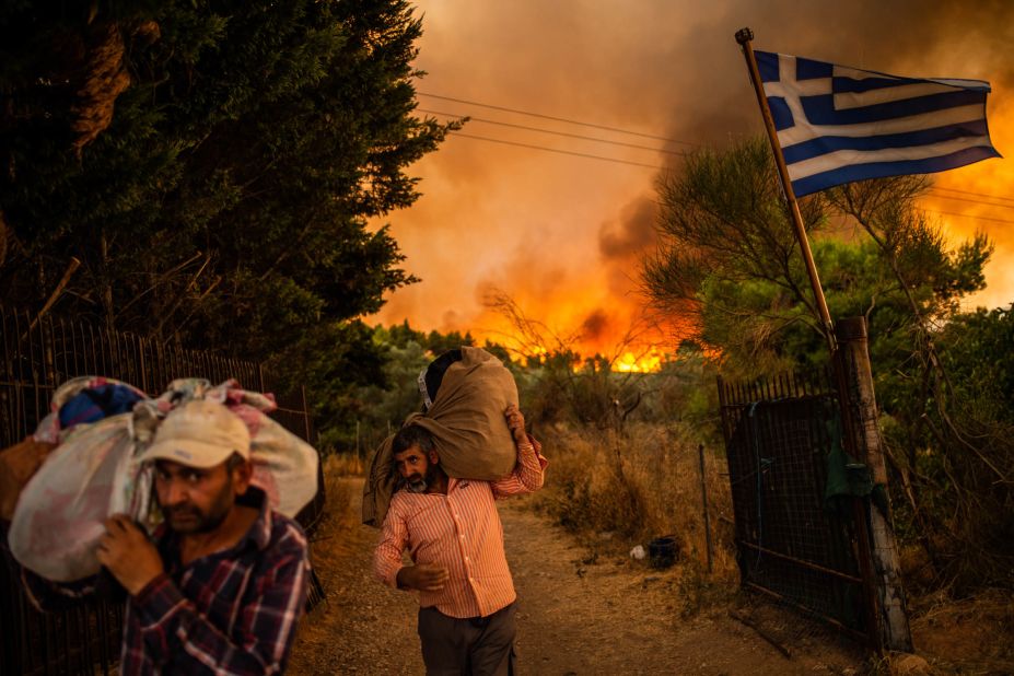 People move belongings to safety as a forest fire rages in a wooded area north of Athens, Greece, on August 5.