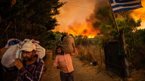 People move belongings to safety as a forest fire rages in a wooded area north of Athens, Greece, on August 5.