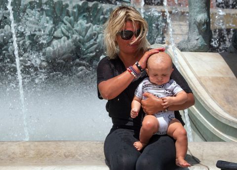 A woman pours water over a baby's head at a fountain in Skopje, North Macedonia, as temperatures reached over 40 degrees Celsius (104 degrees Fahrenheit) on August 2. 