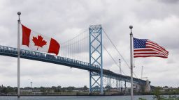 Canadian and American flags fly near the base of the Ambassador Bridge connecting Canada to the U.S. in Windsor, Ontario, Canada, on Wednesday, May 26, 2021. Nearly half of respondents in an Angus Reid Institute poll released Wednesday said the world's longest undefended frontier should remain closed until at least September and more than three quarters said they would support a vaccine passport. Photographer: Cole Burston/Bloomberg via Getty Images