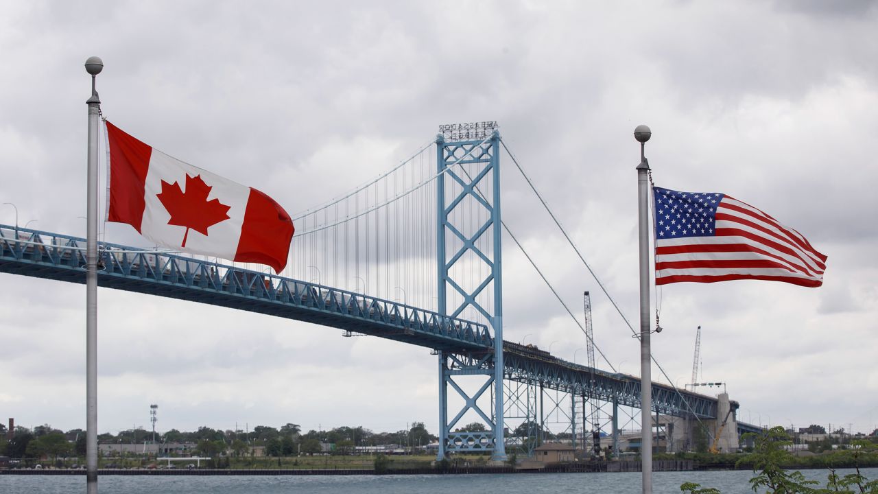 Canadian and US flags fly near the base of the Ambassador Bridge connecting Canada to the United States in Windsor, Ontario.
