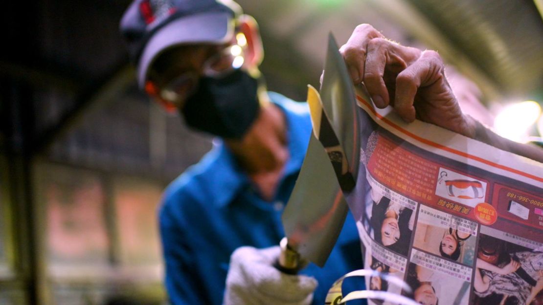 Wu demonstrates the way his knives cut on a piece of newspaper.