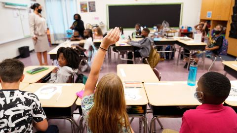 A student raises their hand in a classroom at Tussahaw Elementary School in McDonough, Georgia. Most states are leaving it up to local schools to decide whether to require masks.
