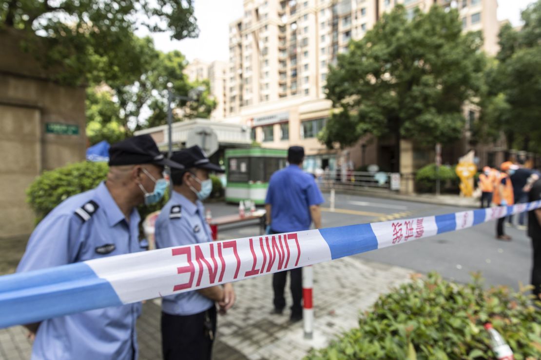 Police, security guards and volunteers help enforce a cordon around a neighborhood placed under lockdown after a resident tested positive for Covid-19, in Shanghai, China, on August 3, 2021. 